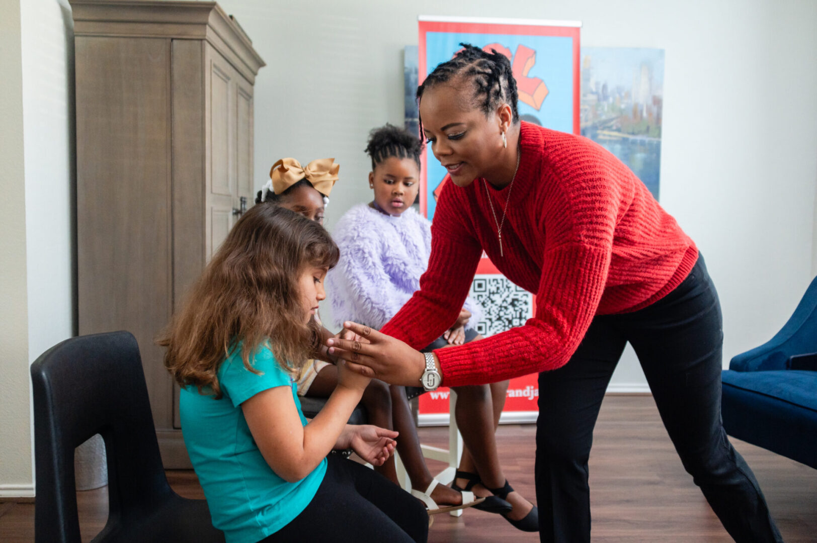 A woman in red shirt touching the hand of a girl.