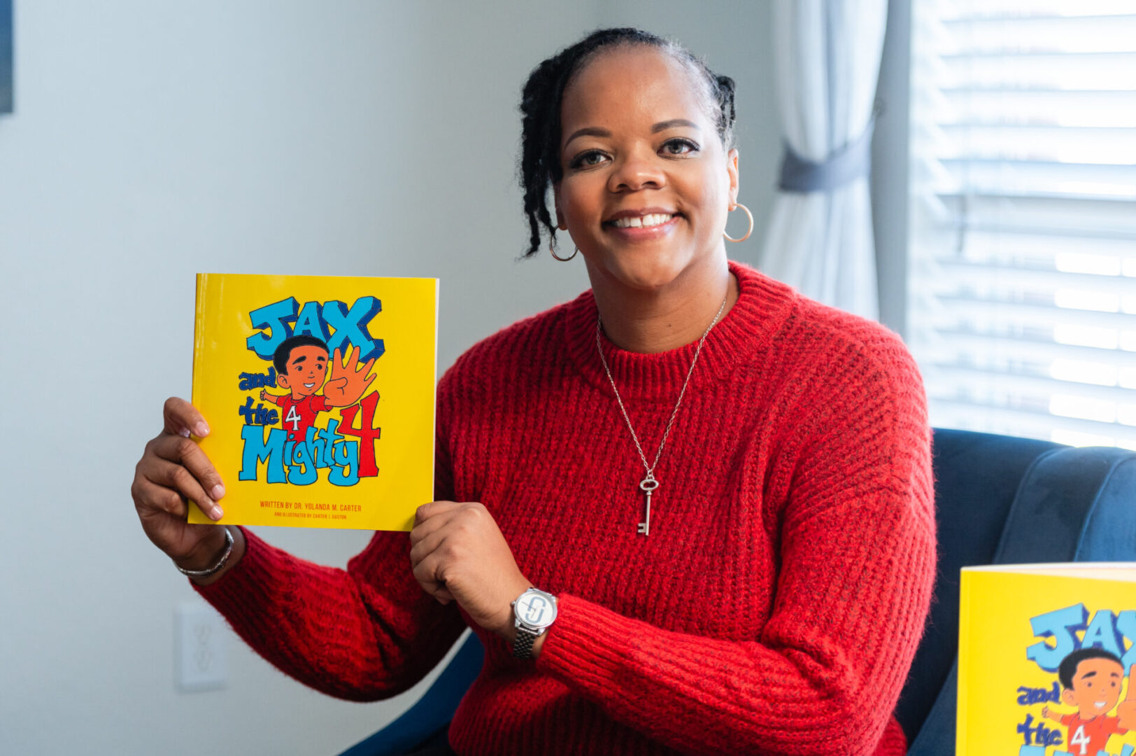 A woman in red sweater holding up a book.