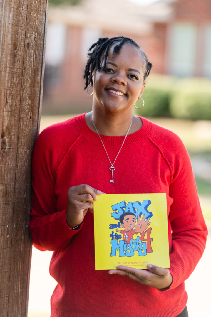 A woman holding up a book with the word " jax " on it.