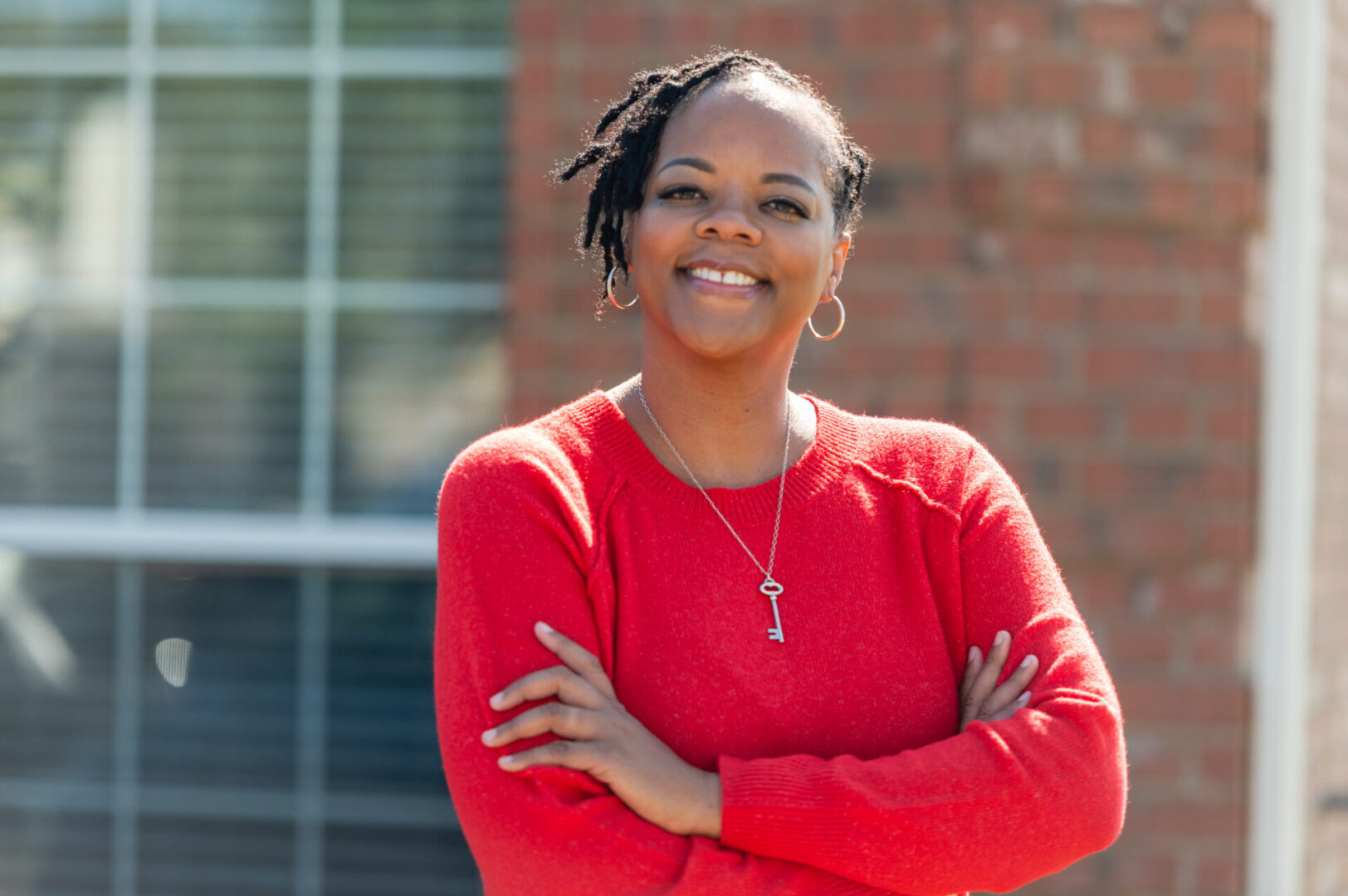 A woman in red shirt standing with her arms crossed.