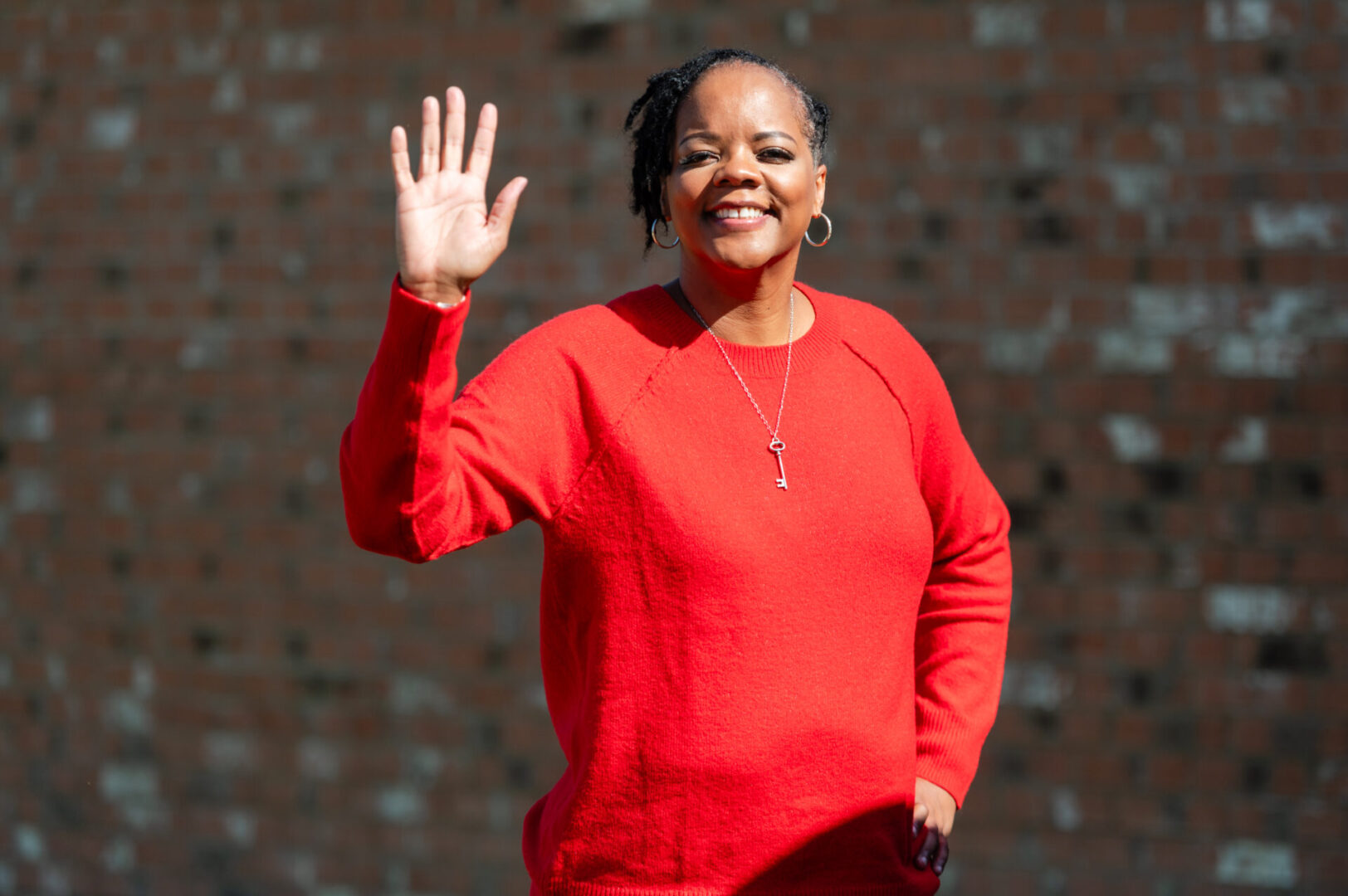 A woman in red waving at the camera.